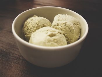 Close-up of ice cream in bowl with spoon on wooden table