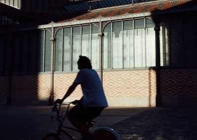 Man riding bicycle on street against building in city
