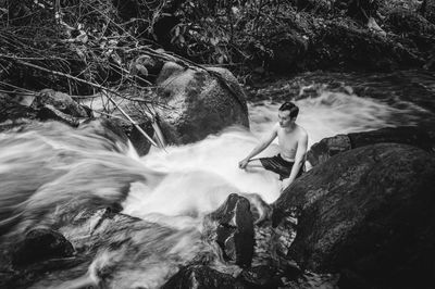 Man sitting on rock by river