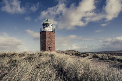 Lighthouse on field against sky