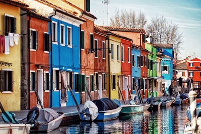 Boats moored in canal by buildings in city