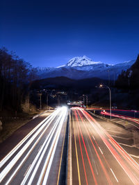 Light trails on road in city against sky at night
