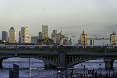 Bridge over river in city against clear sky