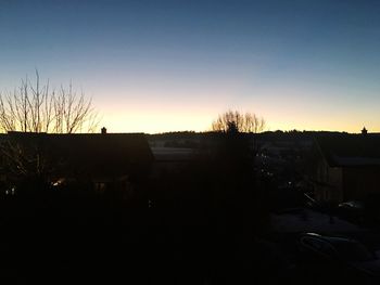 Silhouette houses and trees against sky at sunset