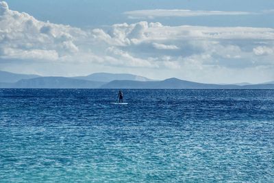 Man paddleboarding on sea against sky