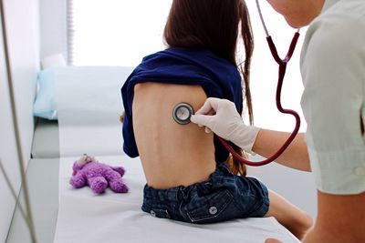 Rear view of patient being checked by doctor at medical clinic