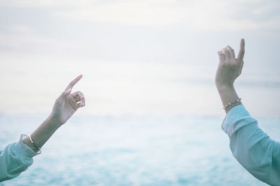 Low angle view of man hand against sea against sky