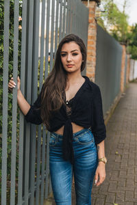 Portrait of beautiful young woman standing against wall