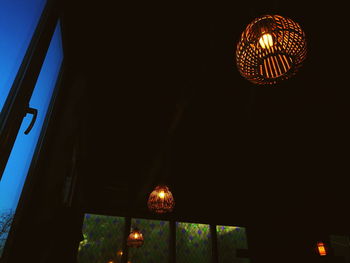 Low angle view of illuminated light bulb hanging at night