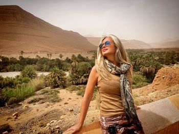 Portrait of young woman standing against mountain