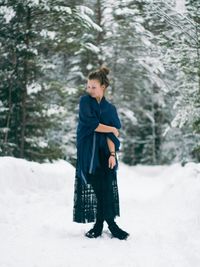 Full length of girl standing in snow covered forest