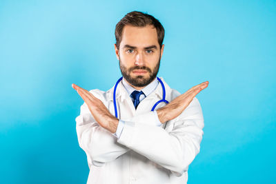 Portrait of young man standing against blue background