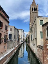 Venetian canal amidst buildings in city against sky