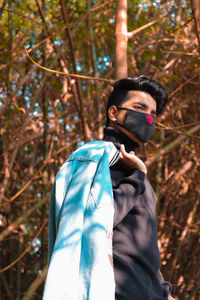 Side view of man wearing mask while standing in forest