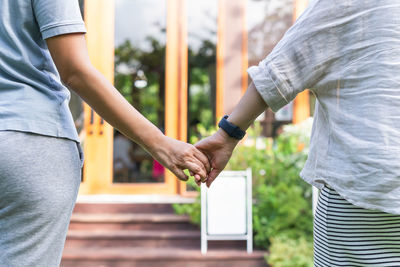 Lgbt woman couple holding hands in the garden outdoors.