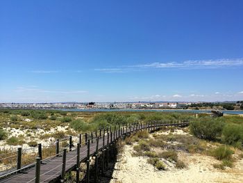 Footbridge over landscape against sky