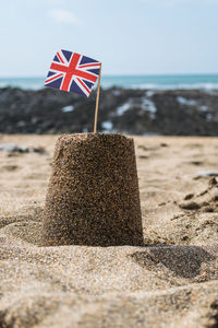 Close-up of flag on beach against sky