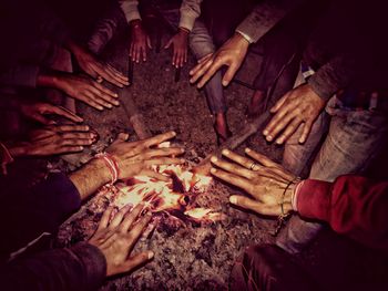 Male friends warming hands over campfire