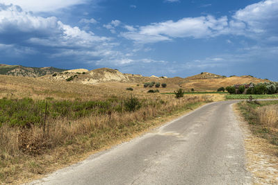 Road leading towards mountains against sky