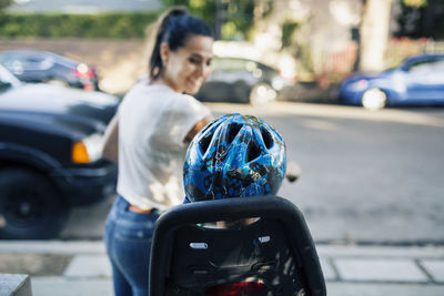 Smiling woman looking son sitting on bicycle by street