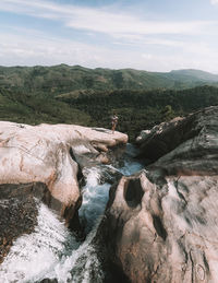 Woman standing on rock formation by river