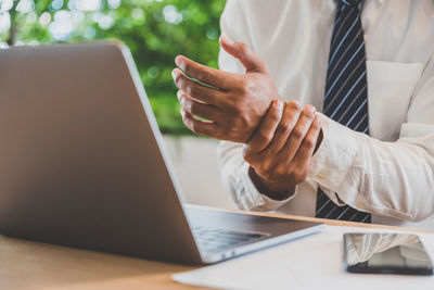 Midsection of man using laptop on table