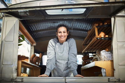 Portrait of smiling mid adult owner standing in food truck