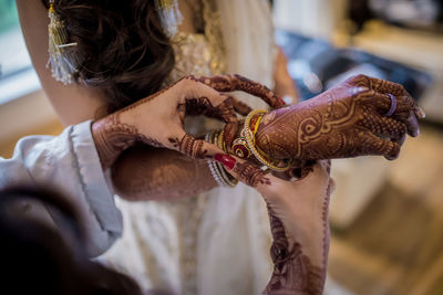 Hand of an indian bride decorated with henna or mehndi wearing gold bangle made with diamond 