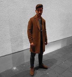 Portrait of young man standing against wall