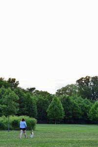 Rear view of people standing on golf course against clear sky