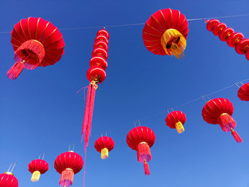 Low angle view of lanterns hanging against clear blue sky