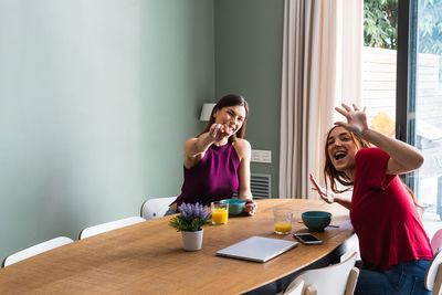 Young woman using phone while sitting on table