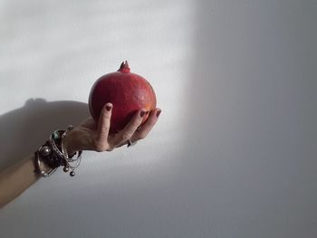 Midsection of person holding apple against wall