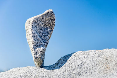 Low angle view of rocks against clear blue sky