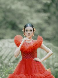 Portrait of young woman standing against trees