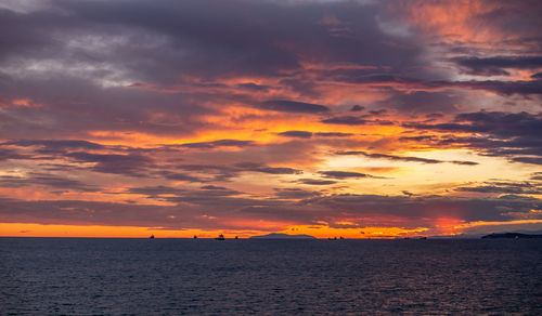 Scenic view of sea against dramatic sky during sunset