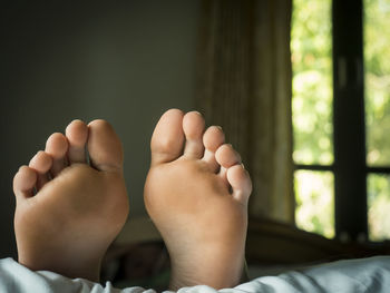 Low section of person relaxing on bed