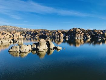 Reflection of rocks in lake against blue sky