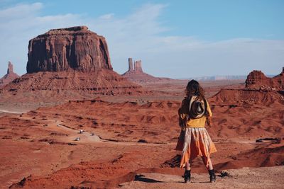 Rear view of woman with hat standing at desert