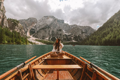 Man sitting on boat in lake against sky