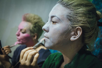 Side view of young women applying make-up 