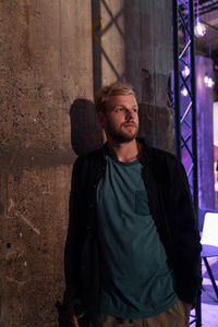 Portrait of young man standing against wall