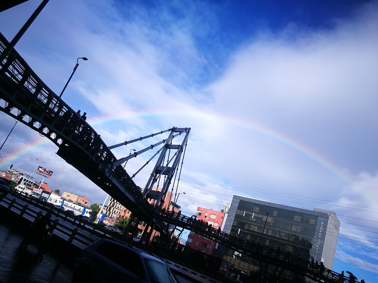 LOW ANGLE VIEW OF CRANE IN CITY AGAINST RAINBOW