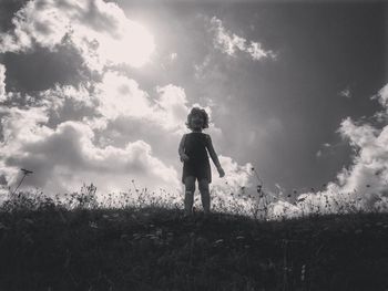 Rear view of man standing on field against sky