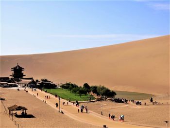 Group of people on crescent lake in in mingsha shan near dunhuang city, gansu province, china.