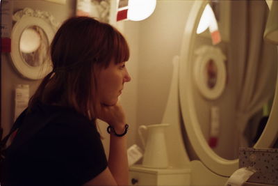 Side view of young woman standing in illuminated room