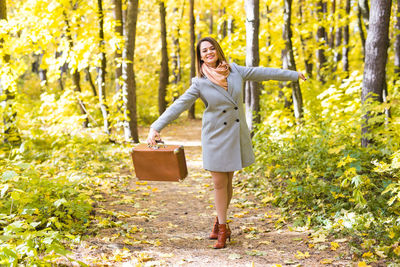 Full length of a smiling young woman in autumn