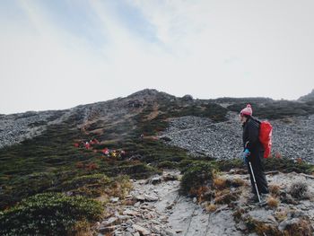 Rear view of man standing on mountain against sky