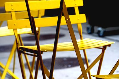 Close-up of empty yellow chairs at sidewalk cafe