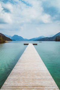 Pier over lake against cloudy sky